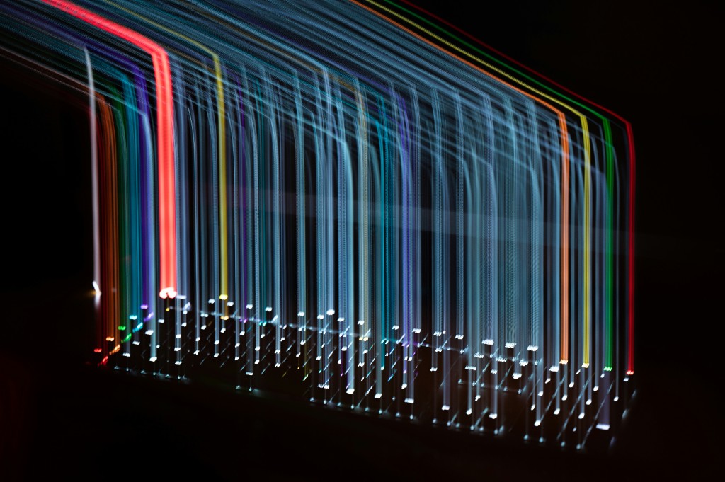 Long-exposure light trails rising from a backlit keyboard against a black background.