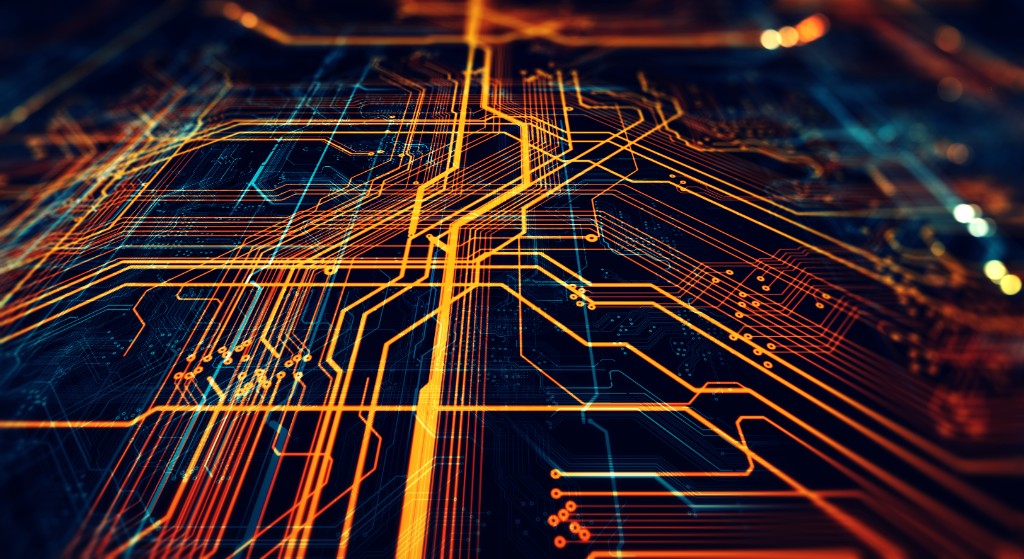Glowing orange and teal circuit board traces on a dark navy background, viewed at an angle.